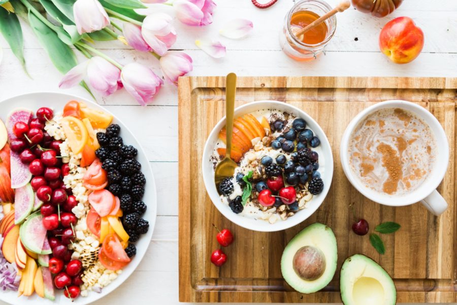 fruit bowl and avocado on wooden cutting board