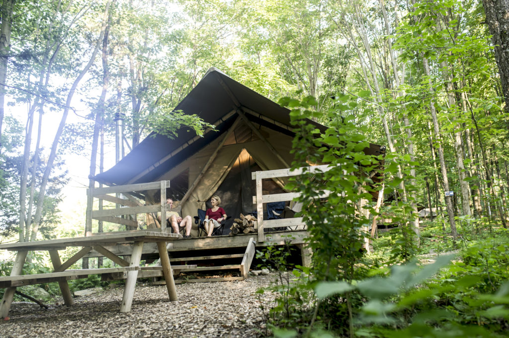 Glampers sit outside their tent-cabin hybrid at Huttopia