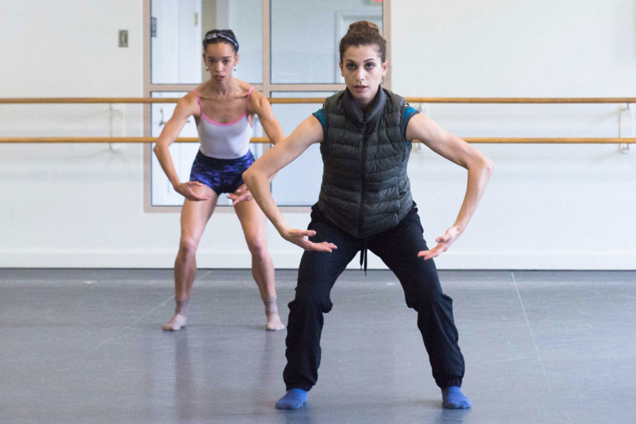 Boston Ballet’s Lauren Flower in rehearsal (wearing sweatpants and a vest) with dancer behind her of a work she choreographed