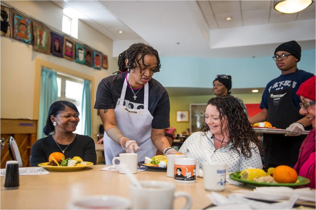 Volunteers serving meals to women in a homeless shelter