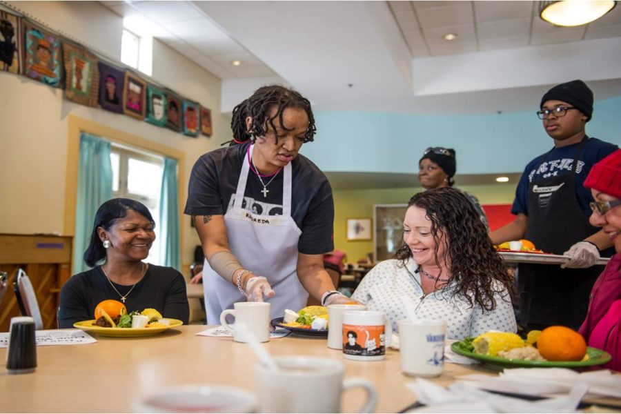 A volunteer serving meals to women in a homeless shelter