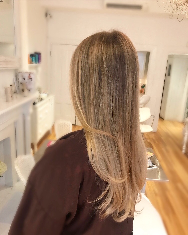 Long blonde hair blown out with curl at the ends seen from the back