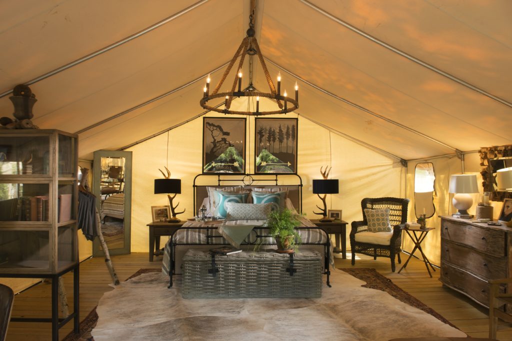 The luxury interior of the Wanderlust tent at Sandy Pines is the epitome of glamping with a chandelier, queen bed with headboard and high-end home furnishings