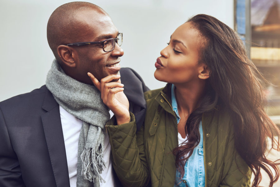 black couple in fall clothing looking into each other's eyes about to kiss