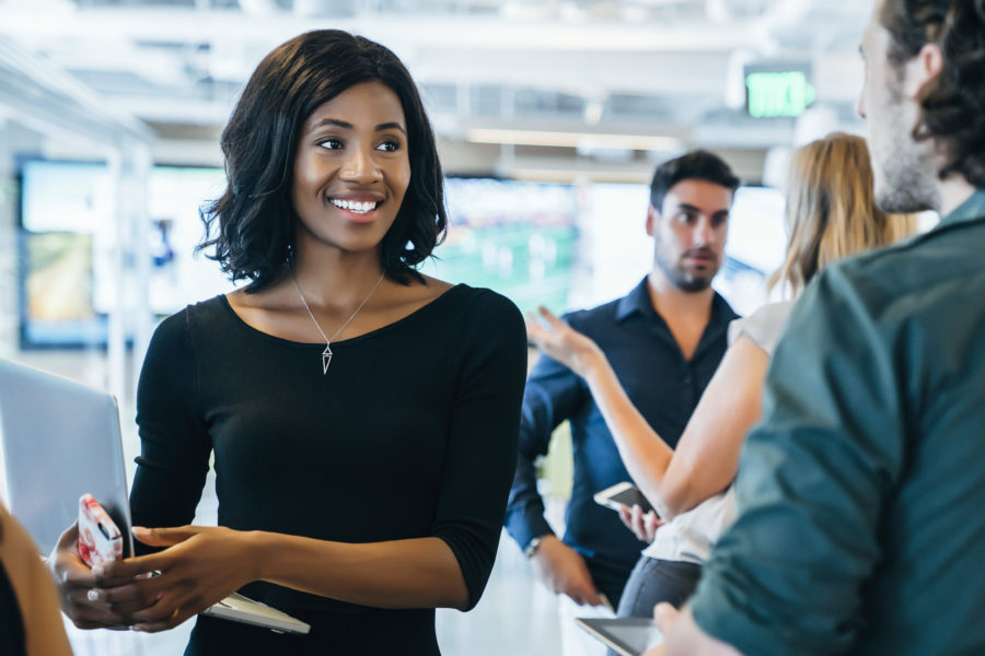 Woman holding laptop and cell phone and talking with other business people