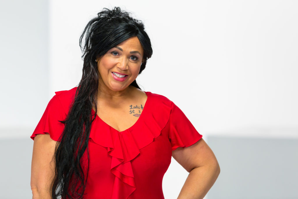 Heart disease survivor in red ruffled shirt with long black hair and tattoo