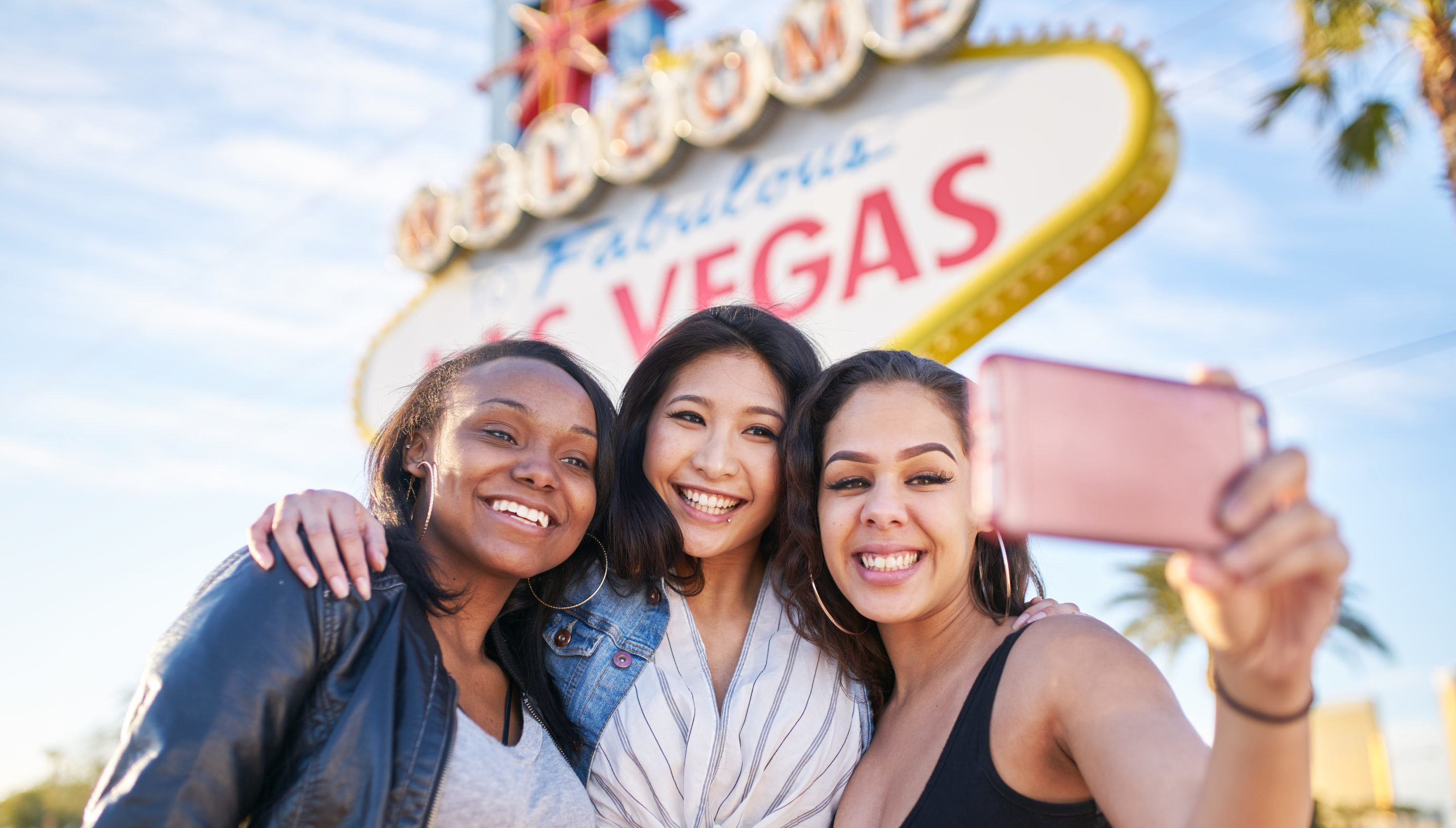 Three young women in front of the Las Vegas sign taking a selfie