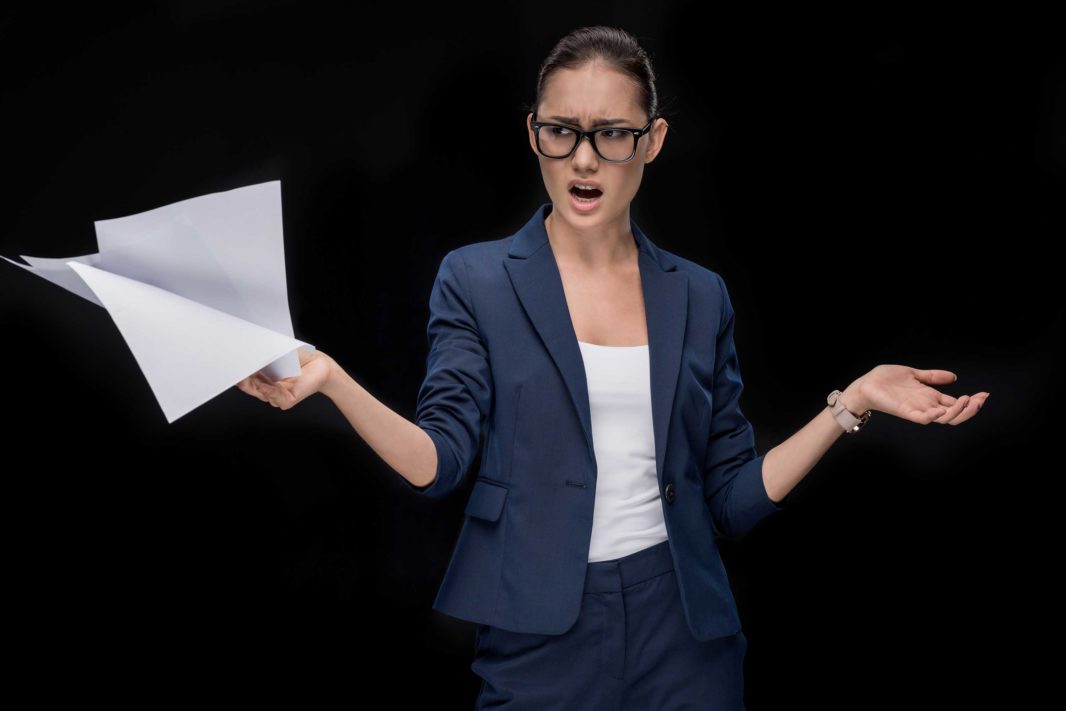 angry woman in navy suit and glasses holding paper