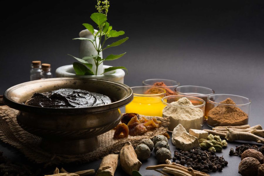 A bowl of Chyawanprash, an herbal jam, surrounded by herbs and spices