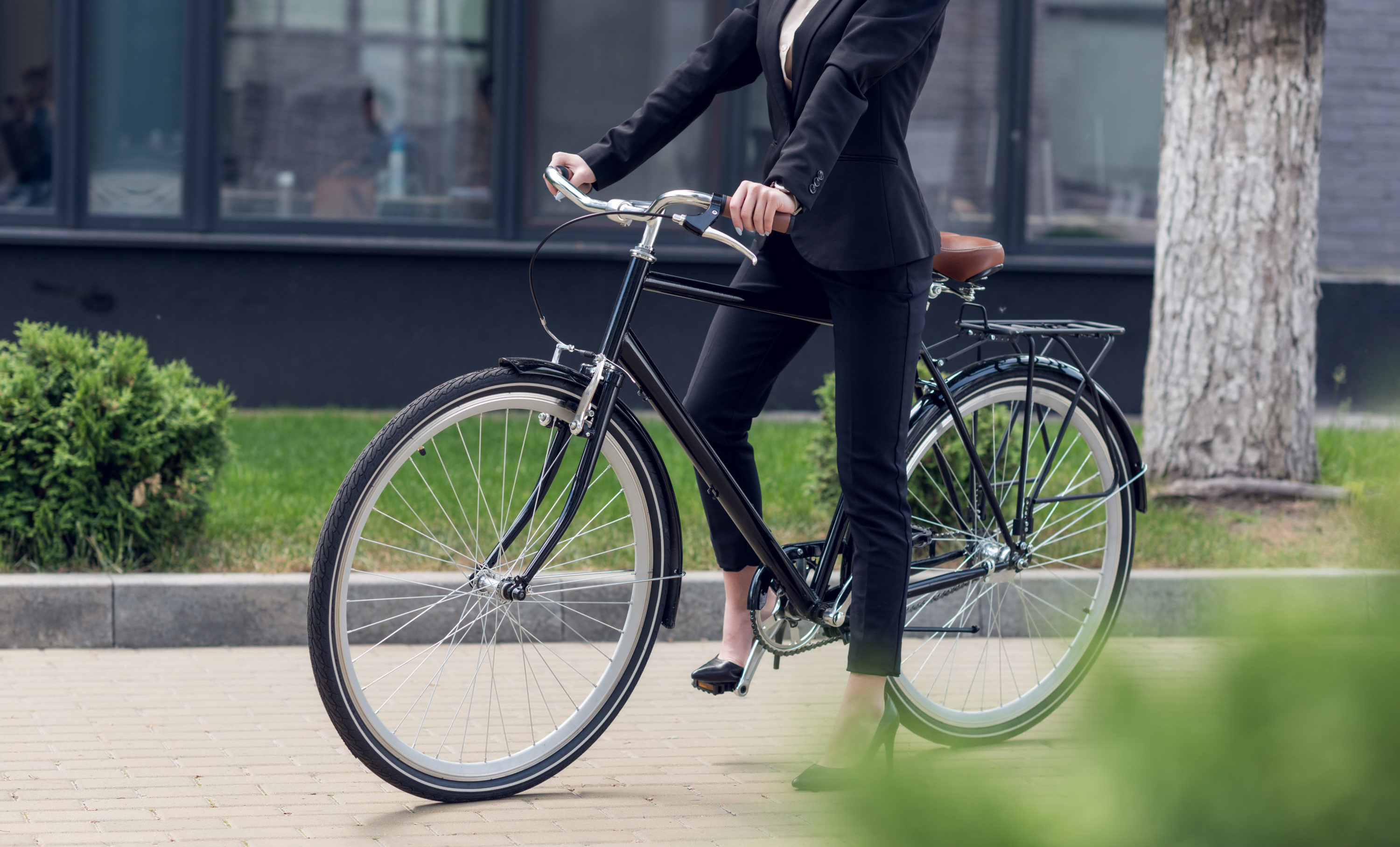 cropped shot of businesswoman in black pants suit with retro black bicycle on street