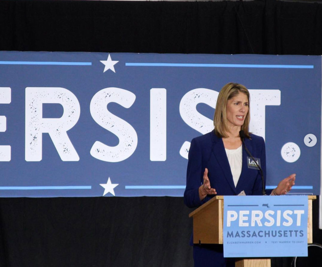 Lori Trahan at podium with "Persist" sign