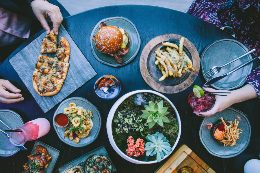 Assortment of colorful food plates around succulent centerpiece on a round dark wood table